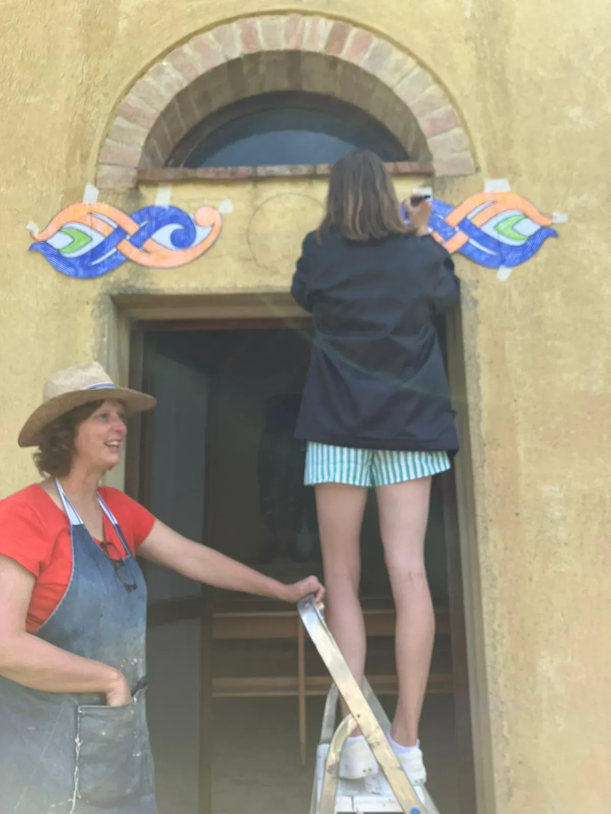 Trina and a helper fixing mosaics over the chapel door