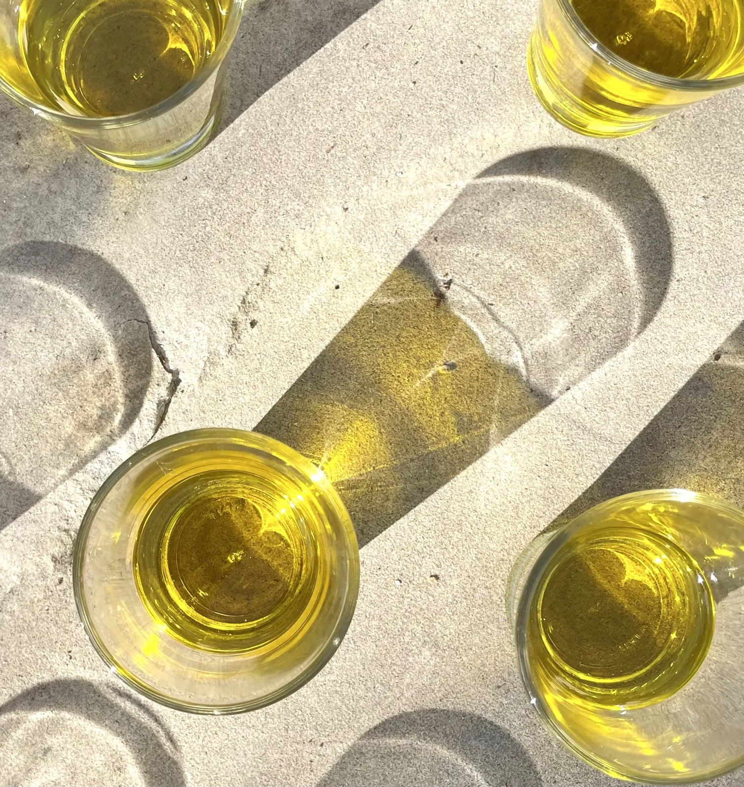 Glasses of new olive oil on a pale stone surface