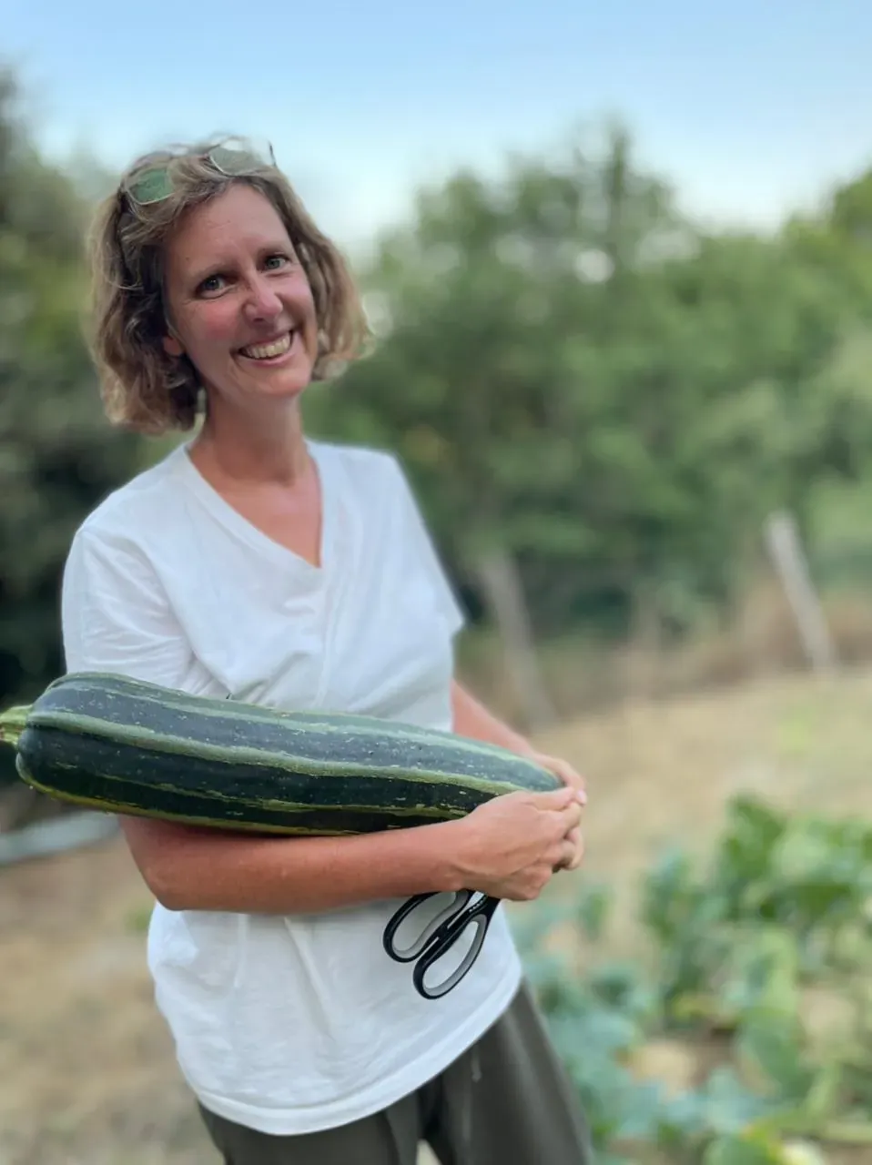 Trina holding a giant zucchini from the orto